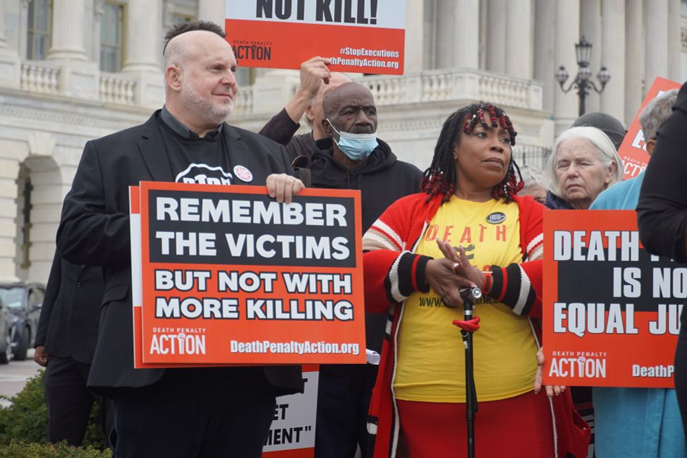 Advocates hold signs at a press conference on commuting federal death row.