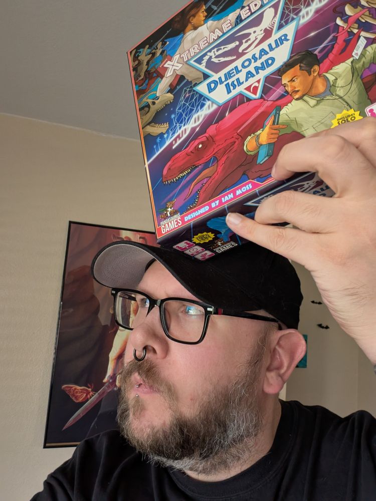 Designer holding Duelosaur Island on top of his head, looking quizical. 