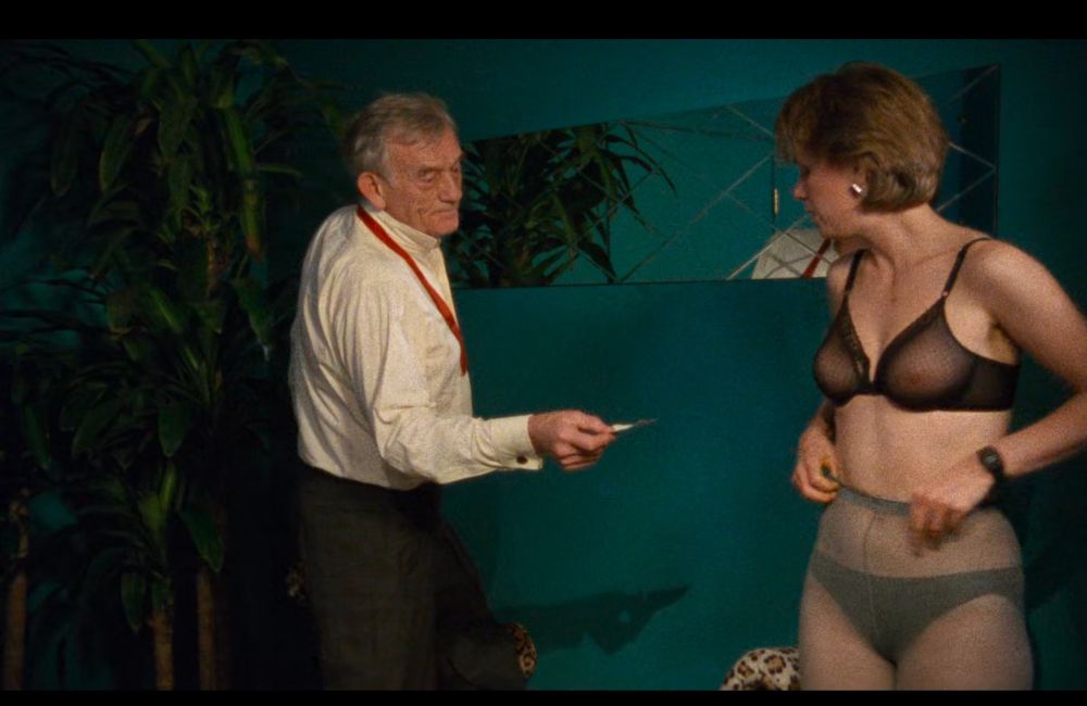 Plan du film avec un homme qui tend de l’argent au personnage principal, en sous vêtements 