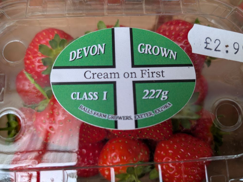 A punnet of strawberries bearing a sticker with the Devonshire flag, and the statement 