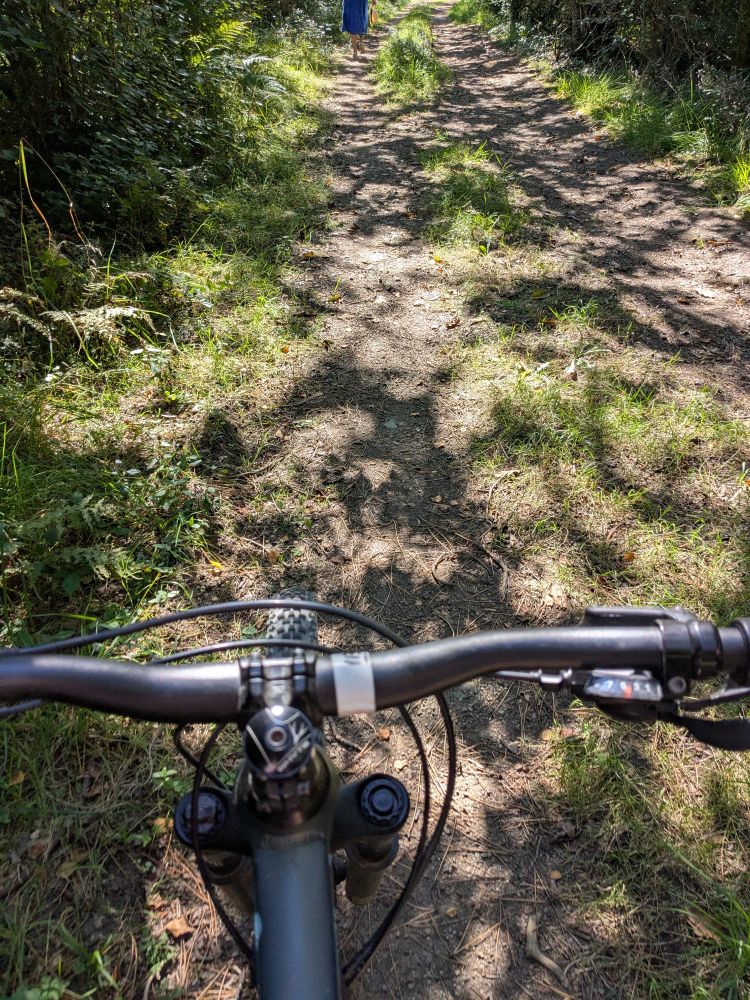 Photo that I took looking over my handlebars, cycling on a bumpy rutted stony path.