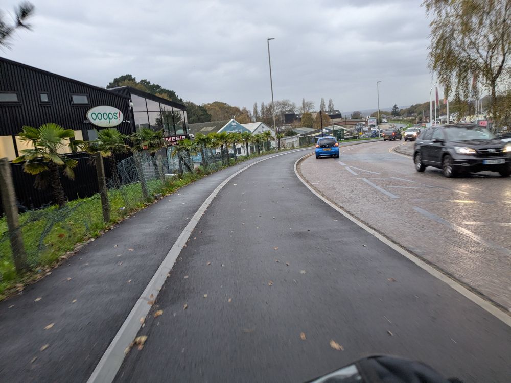 Photo looking along a busy road with a wide segregated stepped cycle track. 