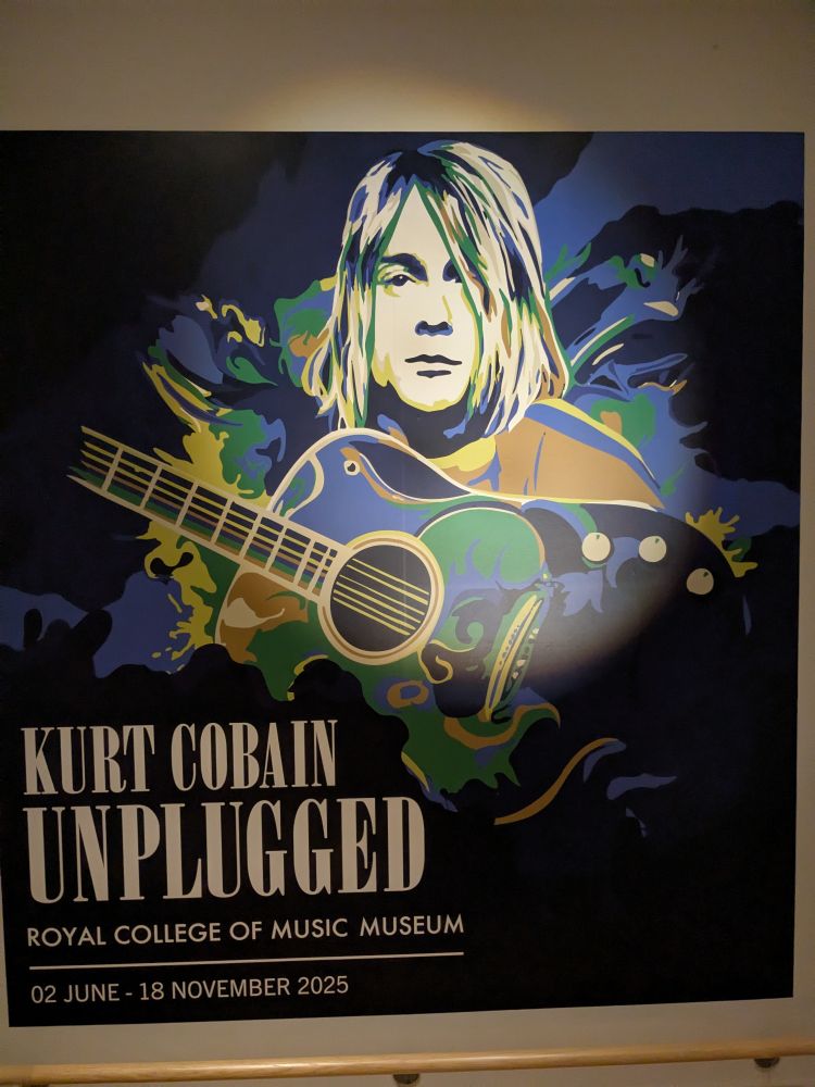 Poster advertising the exhibition, showing a stylised photo of Kurt Cobain and his guitar in blues and greens.