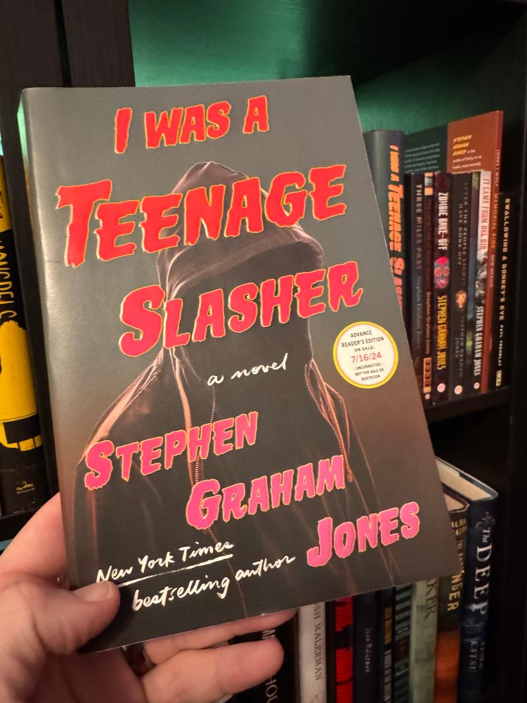 A photo of the Advanced Reader Copy of I Was A Teenage Slasher by Stephen Graham Jones, with other Jones books in the background.