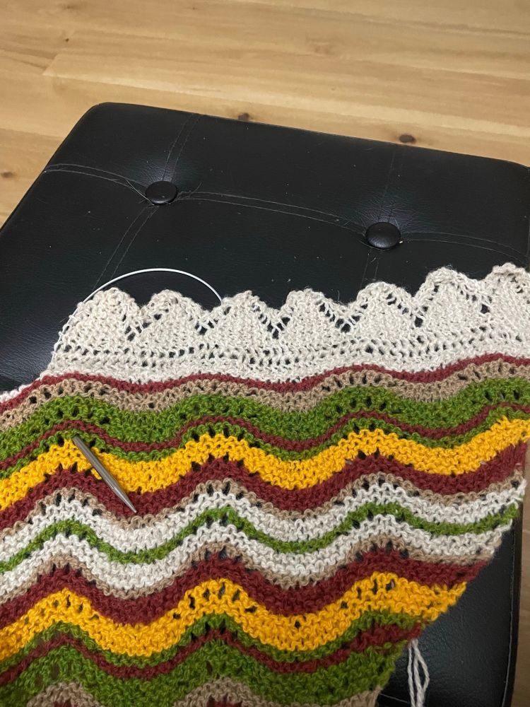 Knitted shawl in various colours with the beginning of an edging 