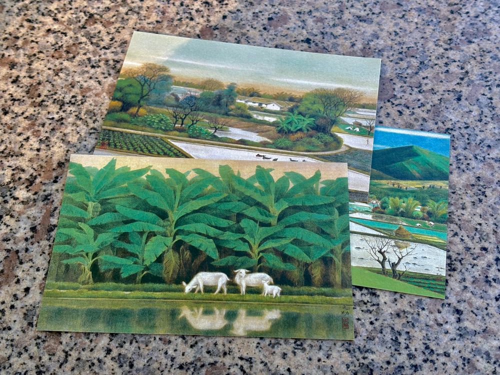 Tres postales sobre un banco de granito. Cada una reproduce una pintura de Lin Chih-Chu, especializado en paisajes taiwaneses serenos. Vemos montañas, arrozales, bananos… El estilo es nihonga (es decir, japonés tradicional) y los tonos son verdes y marrones.