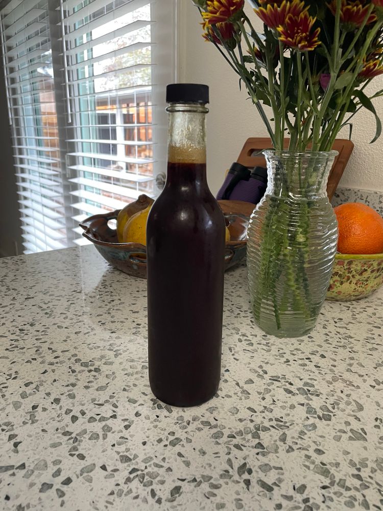 a clear bottle filled with a dark viscous liquid of boiled down fresh grape juice. 