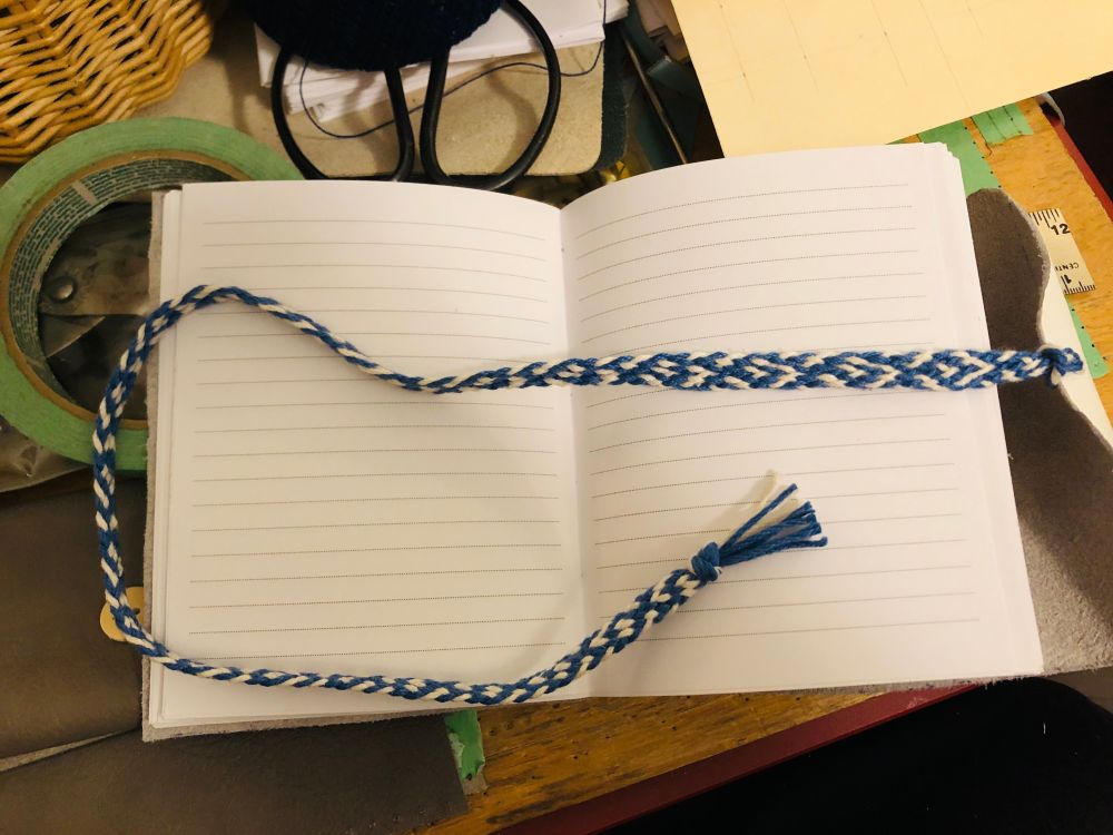 Open lined journal with a fingerloop braid draped across the pages.