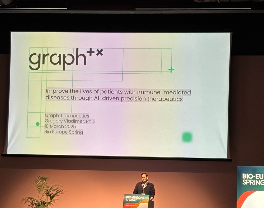 Graph CEO Gregory Vladimer stands at a podium in the center of the BIO-Europe Spring presentation stage with the introductory slide to Graph in the background.