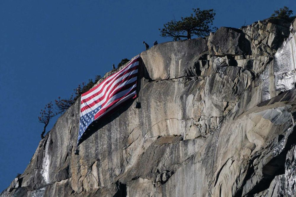 An upside-down American flag hangs from El Capitan near Yosemite National Park’s Horsetail Fall on Saturday to protest the thousands of federal job cuts made by President Donald Trump’s administration. 
Tracy Barbutes/Special to the Chronicle