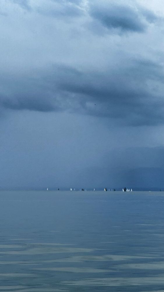 Voiliers sur le lac Léman, depuis la rive de Saint Sulpice dans le canton de Vaud. Sous un ciel d’averses menaçant.