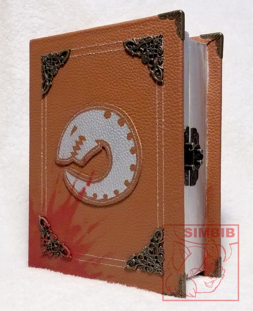 Photo of a wooden box shaped like a heavy book. It is 6" wide and 8" tall and 4" deep. The exterior is bound in a brown pleather. The book opens along the center as a regular book would, and the two halves are closed with a metal latch. The corners of the book along the opening have a bronze corner protector. This book has silver stitching along the outside of the cover with slightly smaller border inside it. Each corner of the exterior edge of stitching has a bronze ornate corner nailed into the cover. The cover has a silver plaque in the middle depicting the Tyranid logo, a circular insect like creature with minimal details. The inner border of the book has silver pages. The bottom left corner of the book has red paint that looks like dried blood splatters.