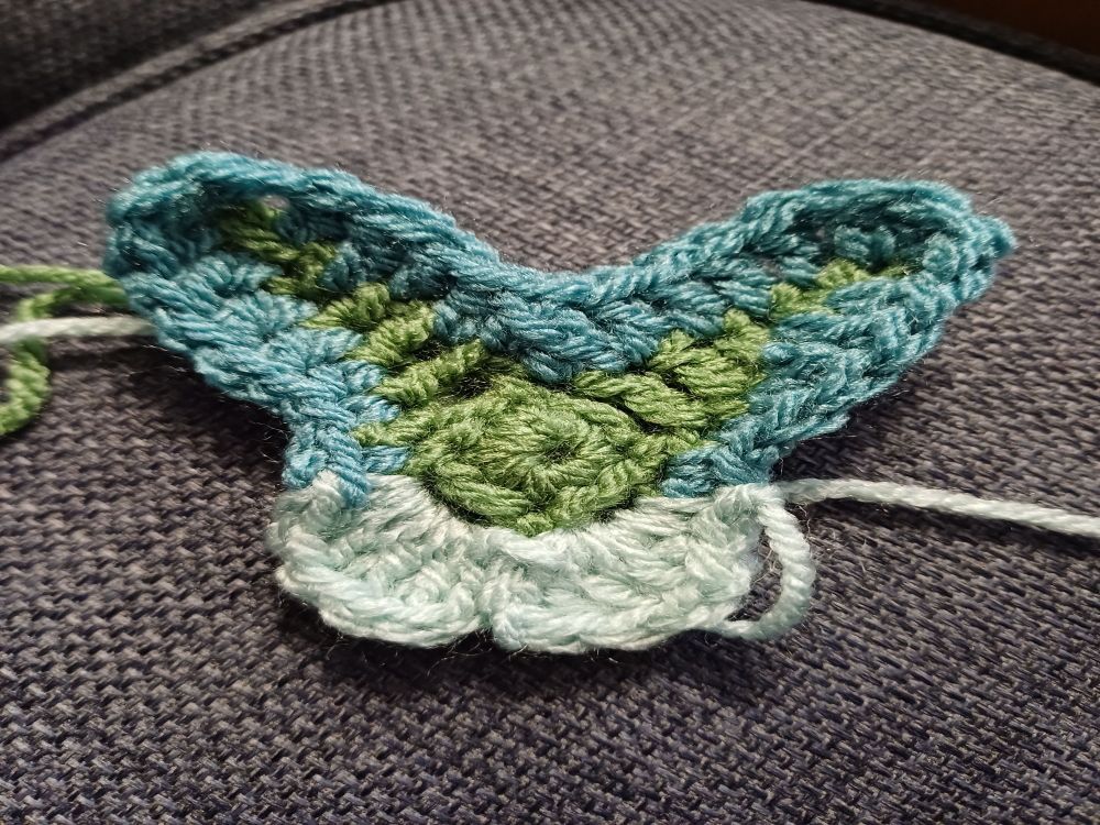 Small crocheted butterfly with dark and blue coloured wings.