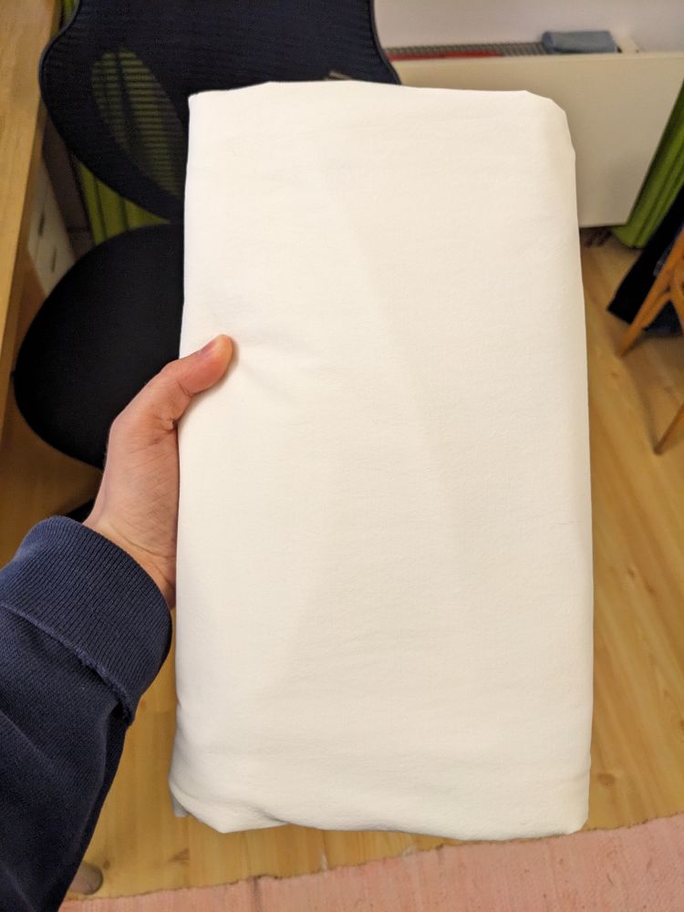 Jag håller i en vit tyg-rektangel dvs ett perfekt vikt dra-på-lakan