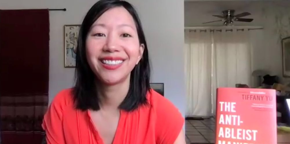 Image of Tiffany Yu sitting beside her book The Anti-Ableist Manifesto.