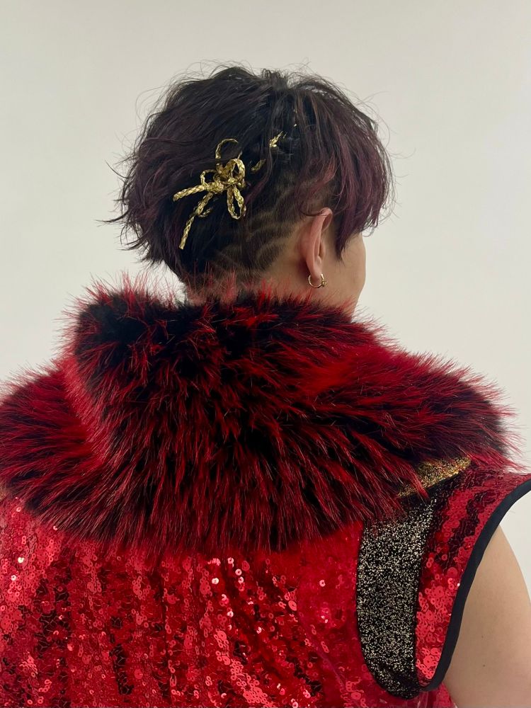 kamio's hair as kuro from the back, a gold hair accessory that looks like a ribbon was tied into part of his short hair sits at the back of his head. the hair at the bottom and behind his ear is shaved short and into a wave design (Seigaiha) 