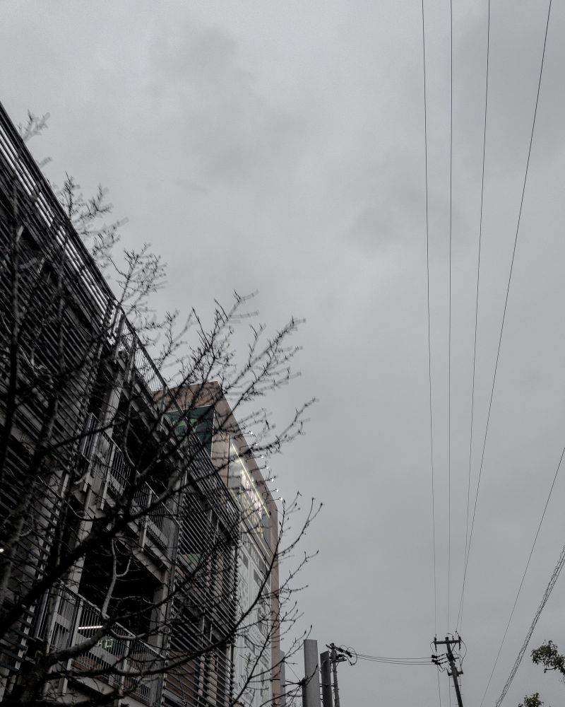 立体駐車場と小雨が降る曇り空の写真