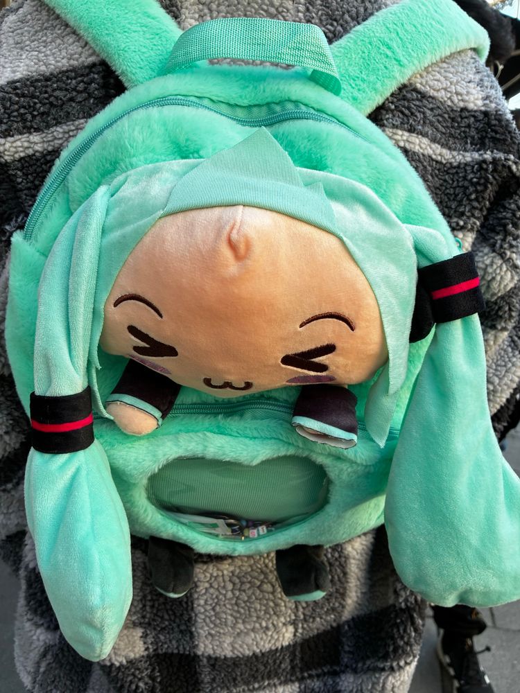 a hatsune miku backpack with the middle part of her her folded up to make her look bald 