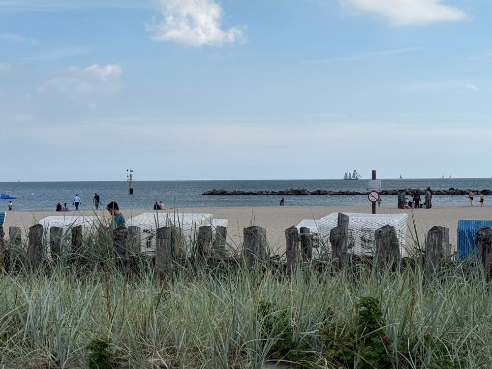 Blick über Düne, Sand, Strandkörbe auf die Ostsee, leicht bewölkter Himmel 