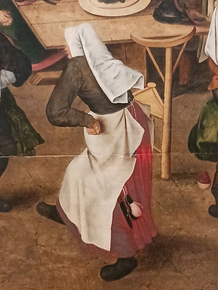 Detail of a woman dancing from a 16th-century painting called Peasant Wedding by Pieter Brueghel the Younger. The woman is turned sideways to the viewer, facing left, and most of her face is hidden by her white headdress. She has her hands on her hips, and it looks like she is mid hop and step. I feel like she is having a good time. 