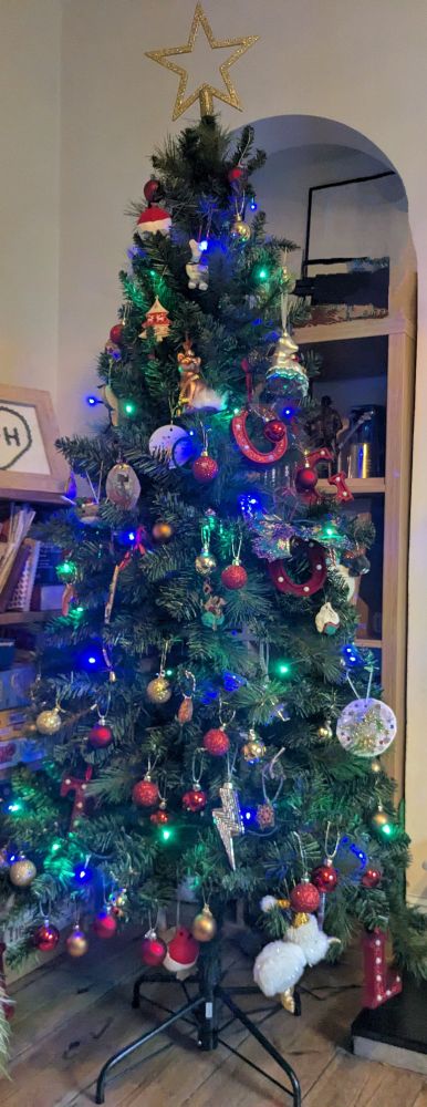 A Christmas tree covered in an extremely broad and diverse set of decorations including multiple shop bought and home made ones