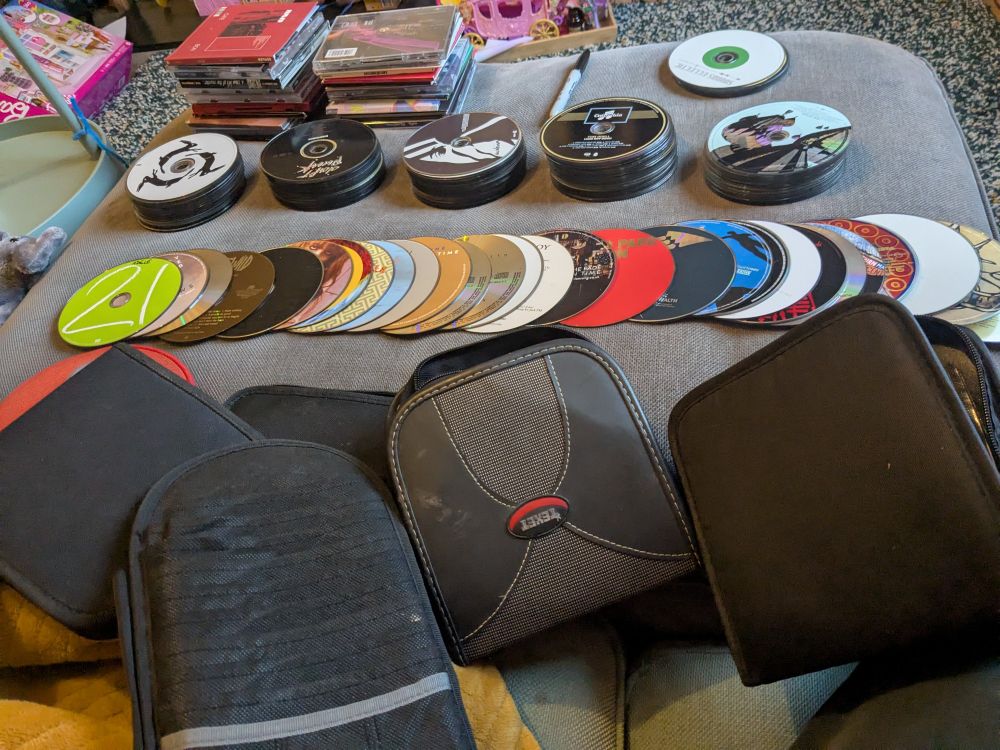 Piles of alphabetised CDs and cd holders ready to be alphabetised, there are hundreds of CDs, mostly of music from 1997 to 2015