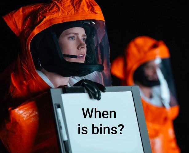 A meme of an image from the film Arrival with a character holding up a sign to the aliens to read, she is wearing a hazmat suit. The sign reads "when is bins?"