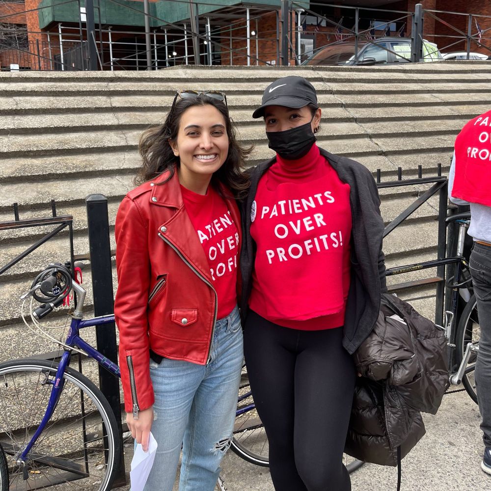 Sarah posing with a nurse after the bike rally. They are both wearing “Patients Over Profits!” shirts.