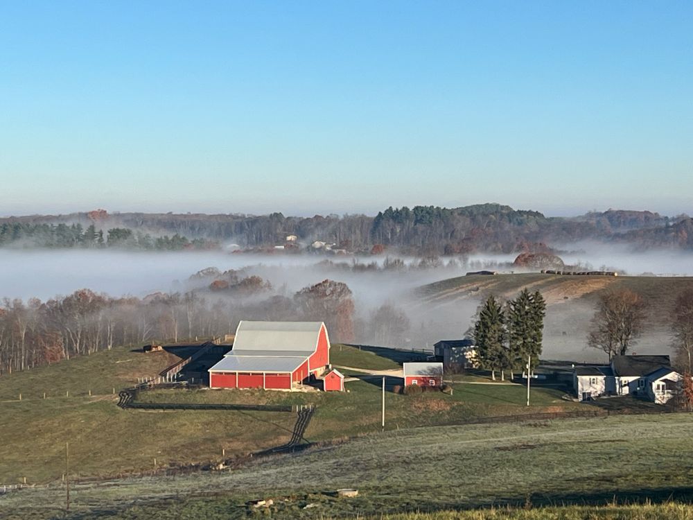 Farm with red barn in the Eastern Ohio hills. Behind the barn, mist settles in ravines and valleys.
