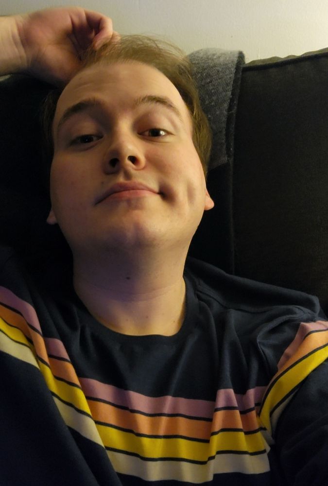 A selfie of me in a dark blue & multicolored-stripe shirt.
