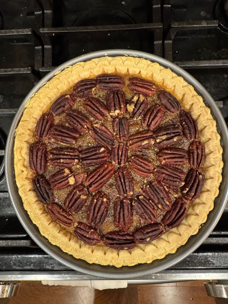 Chocolate pecan pie on a stove. The pecans on top are arranged radially.