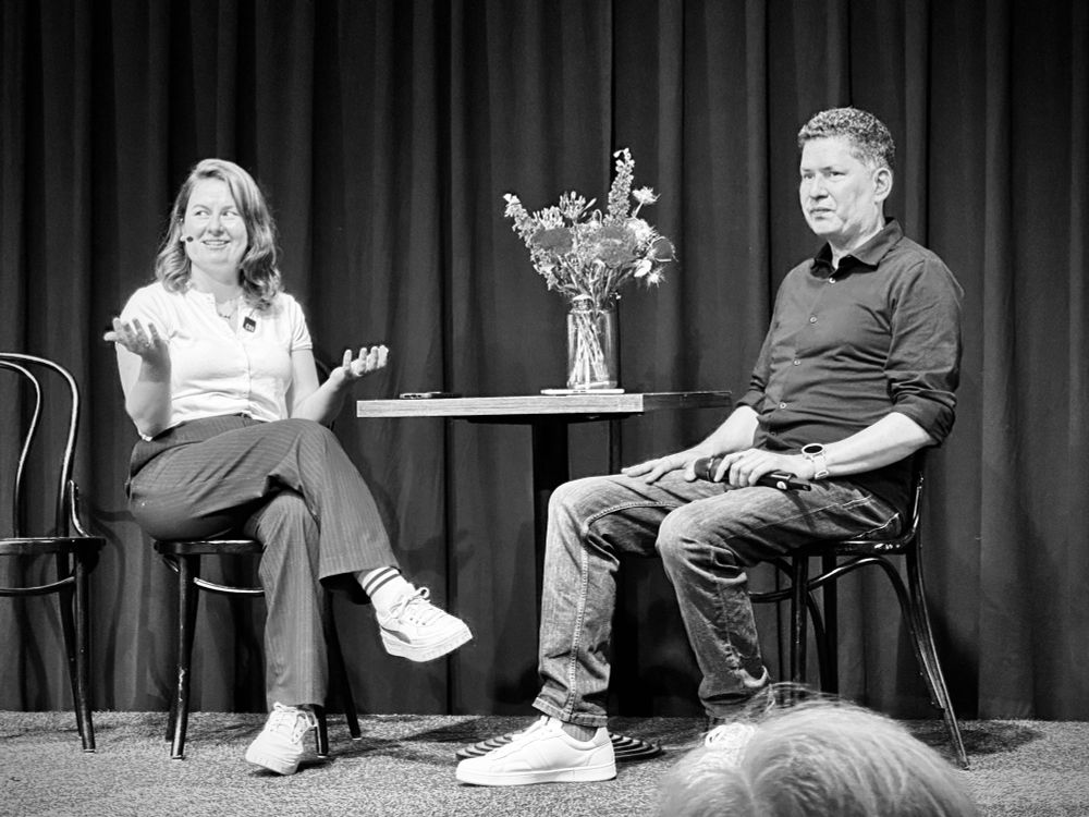 Syd and Stephen Hay sitting at a table with a bouquet of flower on stage. 