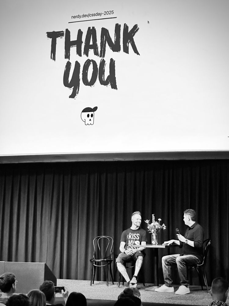 Adam and Stephen Hay sitting at a table on stage after Adam’s talk