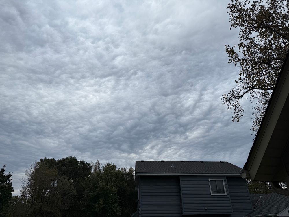 Heavily textured grey and white asperitas clouds fill the sky over a neighboring house.