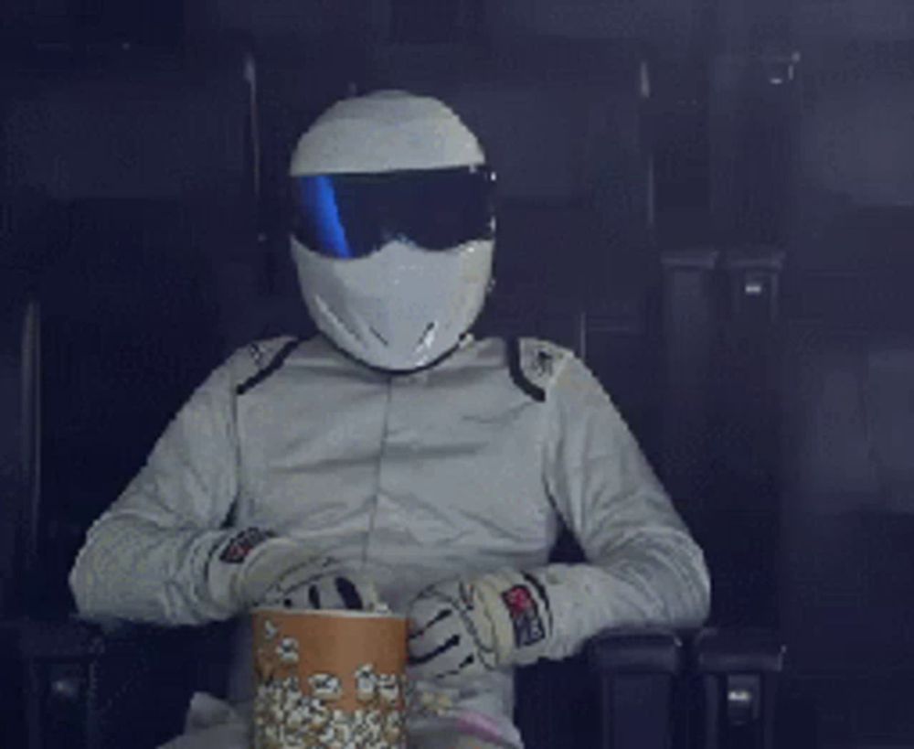 a man wearing a helmet and goggles is eating popcorn in a dark room