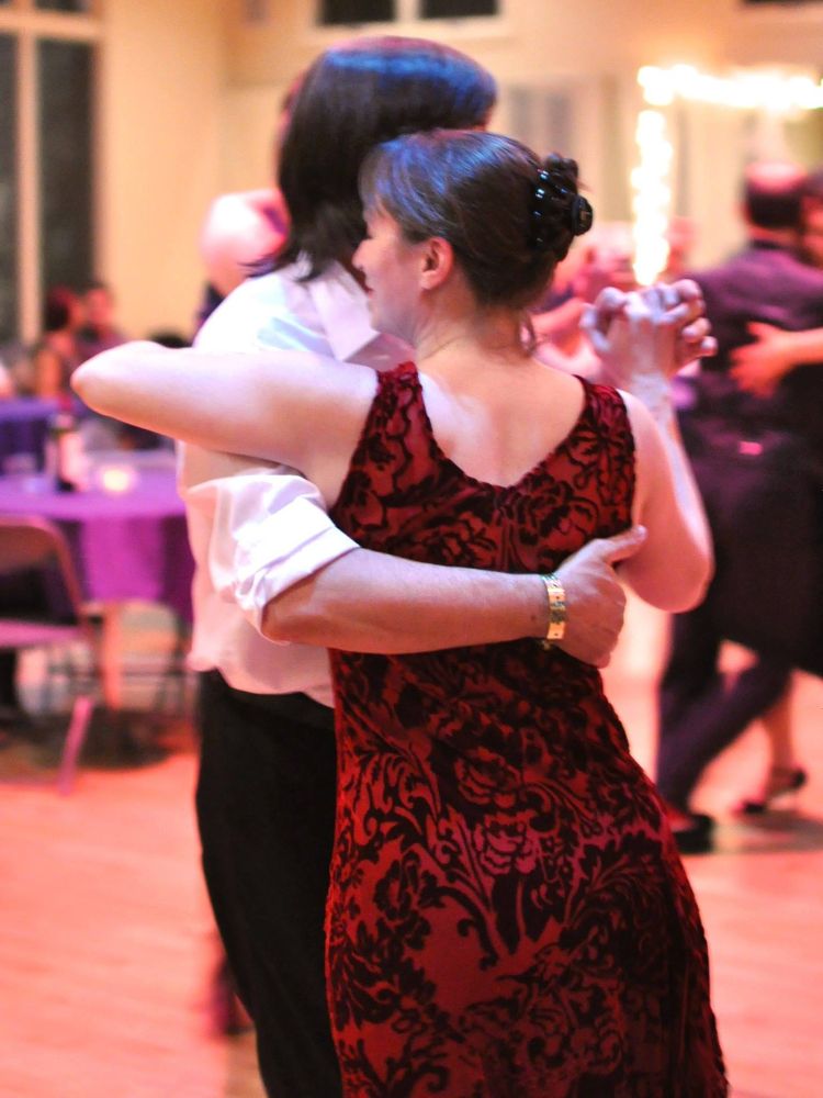 Author of post, a woman in a red dress, dancing with a man in a milonga.