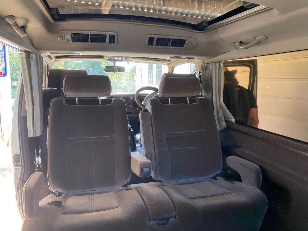 Interior of a Toyota Hiace van with seats facing “back” to the rear