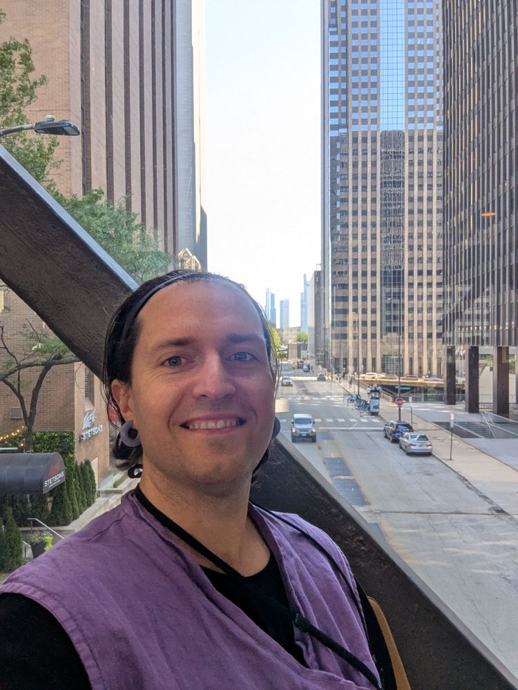 Yours truly looking cute on a skybridge with tall buildings and a large road in the background 