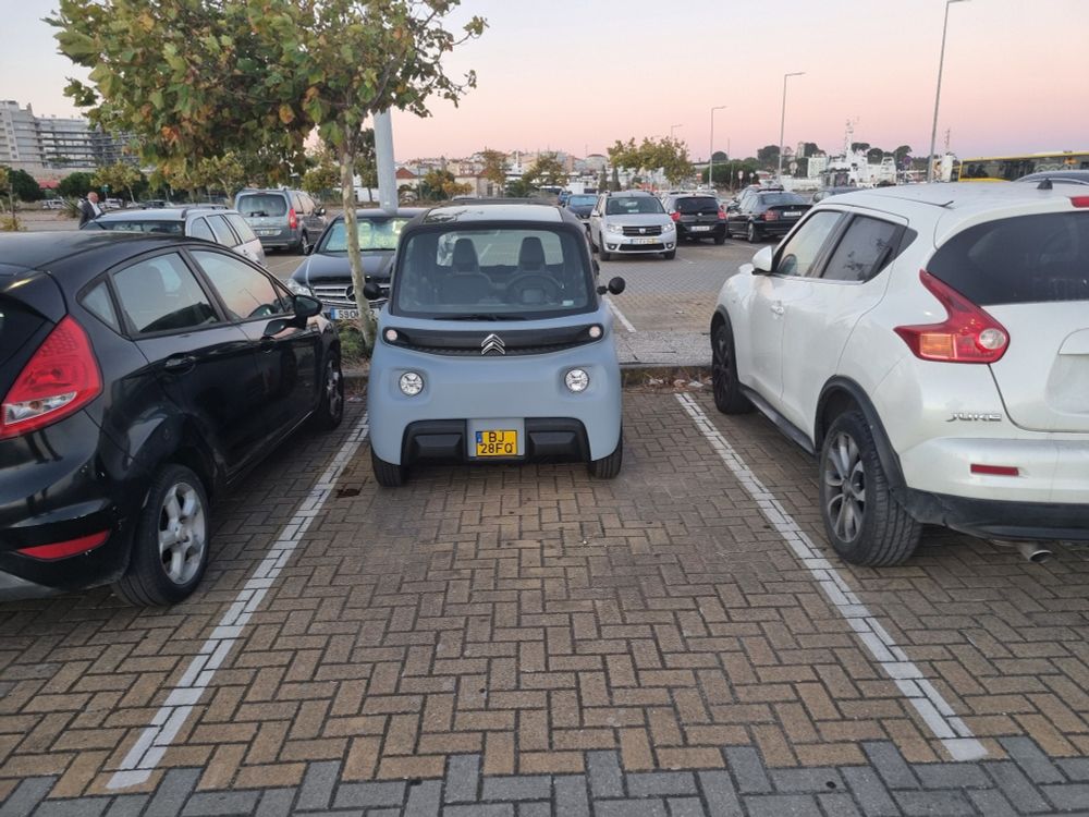 Citroën AMI garée au fond de la place entre un crossover et une sedan laissant beaucoup de place devant