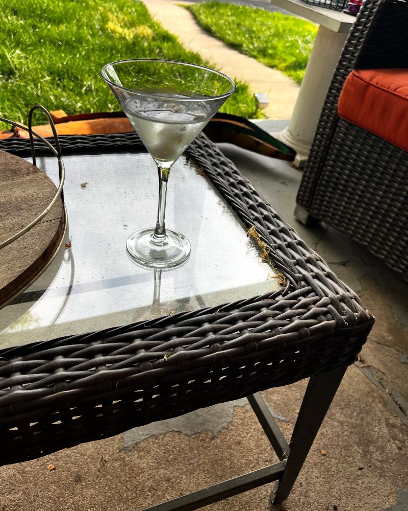 Gibson martini, gin, dry vermouth, and cocktail onions, in a martini glass on a wicker porch table.