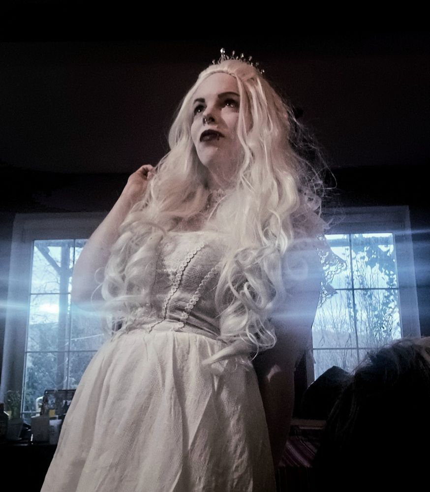 Ein Bild von mir. Ich trage ein weißes Kleid, einen weißen Choker, eine lange, weiße, wellige Perücke, und eine Tiara 
Meine Lippen sind dunkelrot geschminkt, mein Gesicht ist sehr blass geschminkt, meine Augenbrauen dunkel. Die Vorlage dafür war die weiße Königin aus Alice im Wunderland 