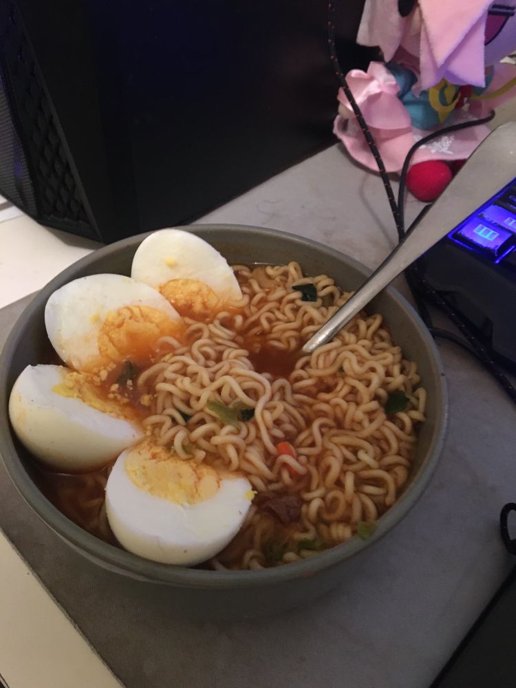 A photo of instant noodles with two boiled eggs sliced and placed in the bowl.
