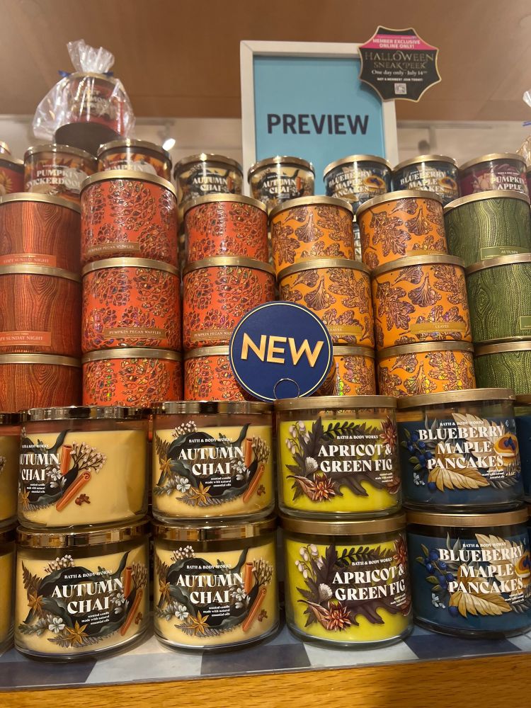 Image of candle display at bath and body works shows fall scented candles blueberry maple pancakes and autumn chai with orange and yellow and dark blue and green colors