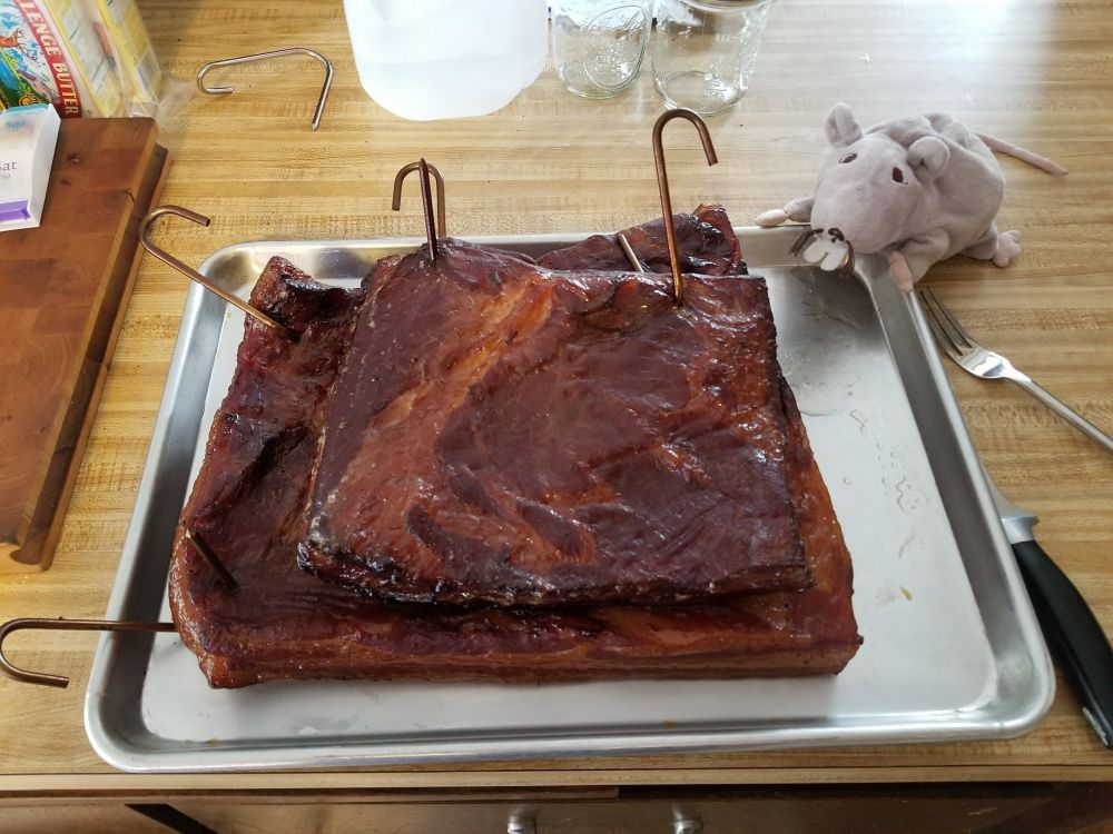 A cute Ikea rat admires beautiful, smokey slabs of home smoked, home cured bacon.