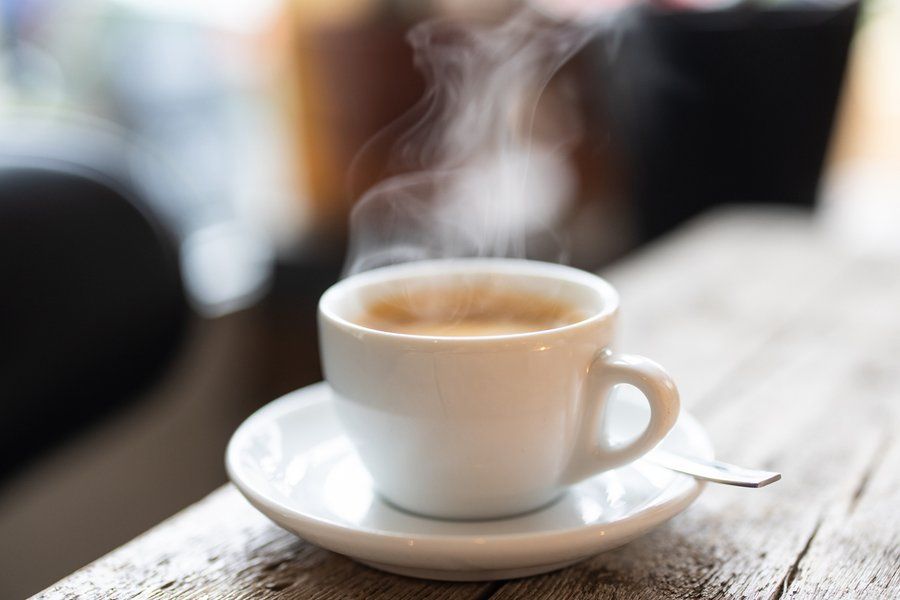 White ceramic coffee mug full of coffee on a cafe table. 