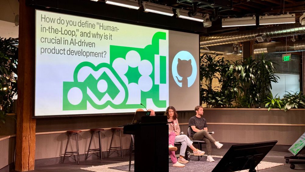 Photo of panelists discussing “How do you define Human in-the-loop, and why is it crucial in AI driven product development?” On the screen behind them.