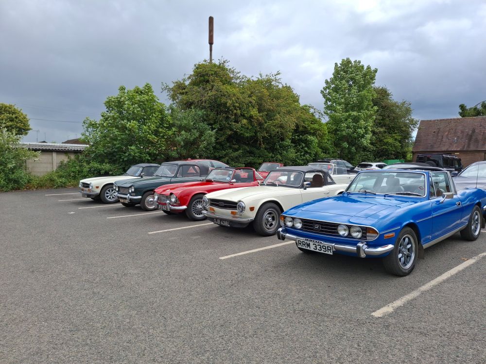Some classic Triumph cars parked in a row. Stag and TR6 amongst them.