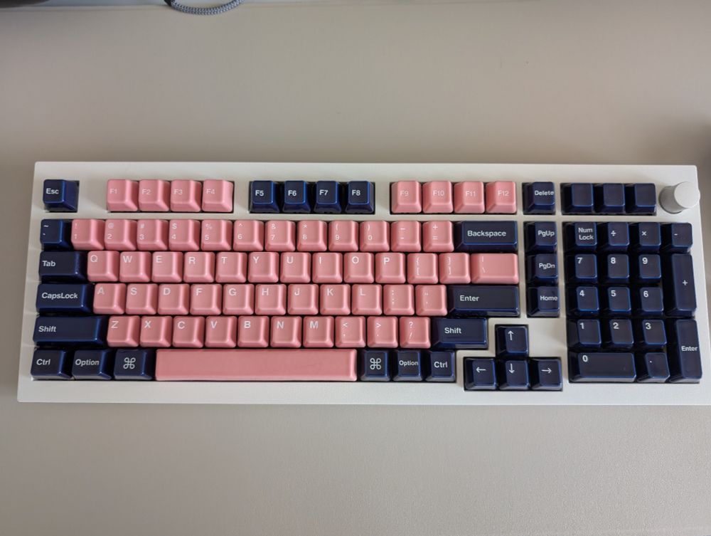 A white 96% keyboard with pink and indigo ceramic keycaps. 