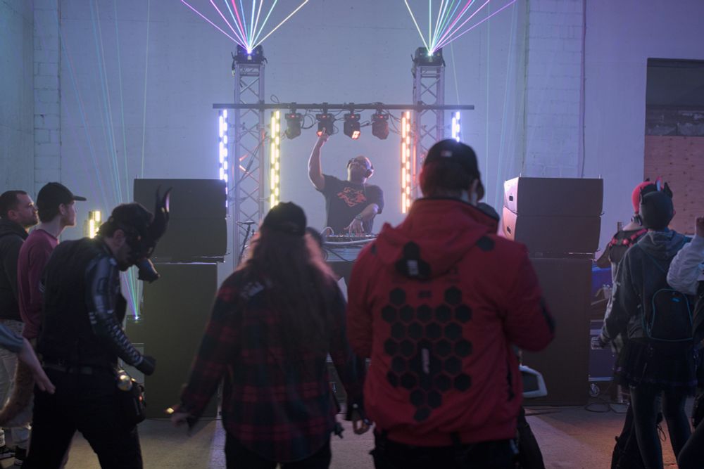 A photograph of Recca DJ'ing for a small crowd.