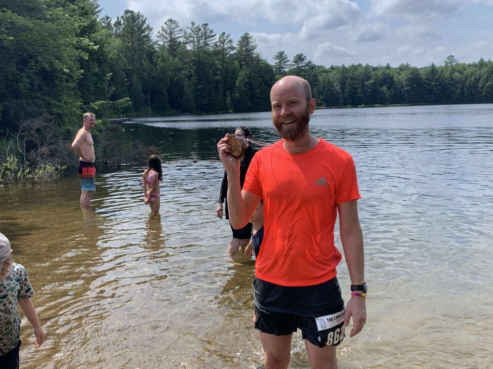 Paul standing in a lake after his race showing off his medal
